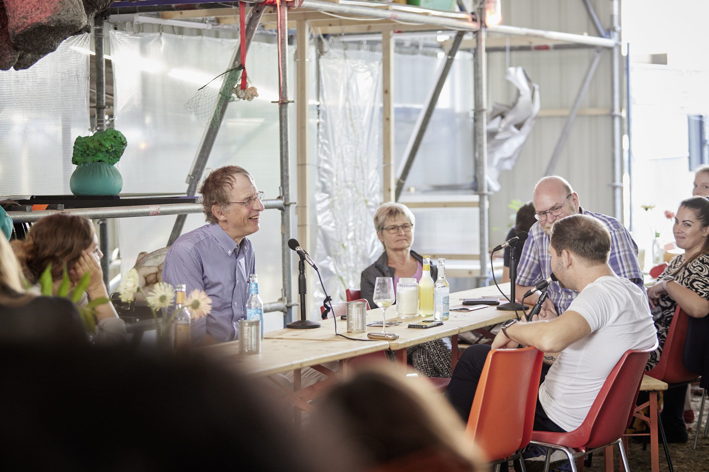 Gesprächsrunde an der langen Tafel, Teilnehmende hören einem Sprecher zu.