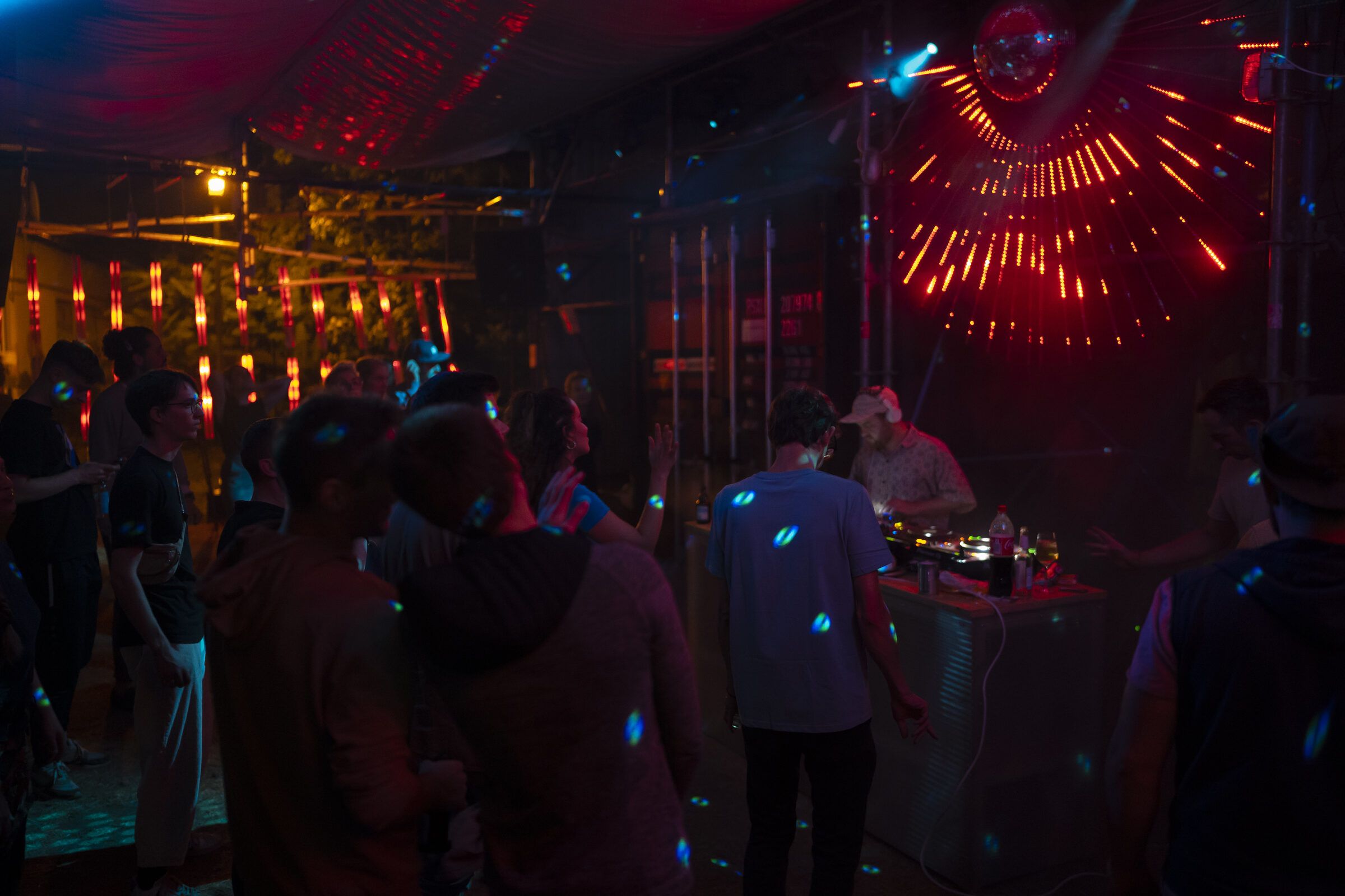 Tanzende in der dunklen Halle, rote Laserlinien und Lichtfächer über ihnen.