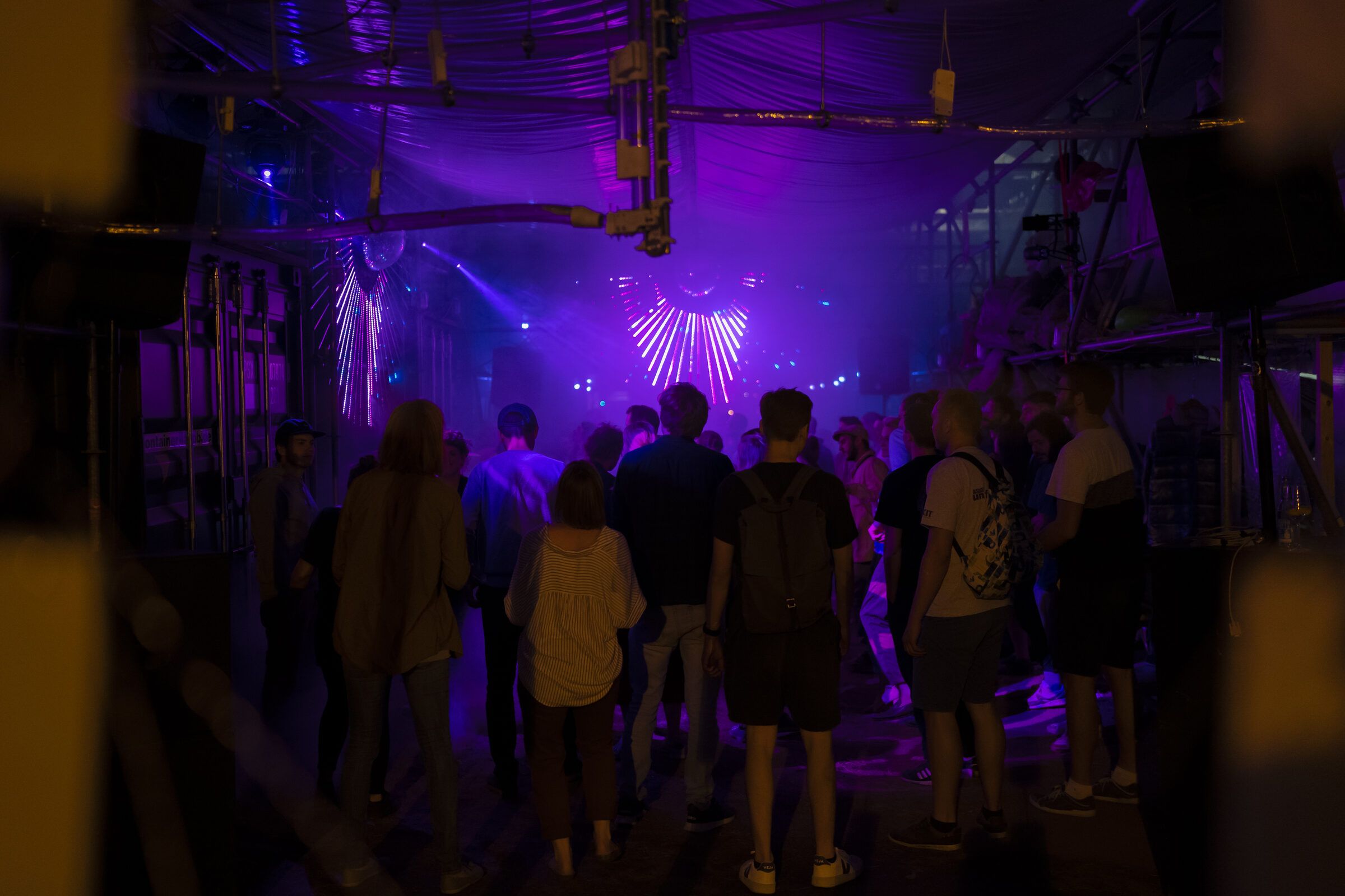 Menschenmenge auf der Tanzfläche unter violettem Licht und Nebel.