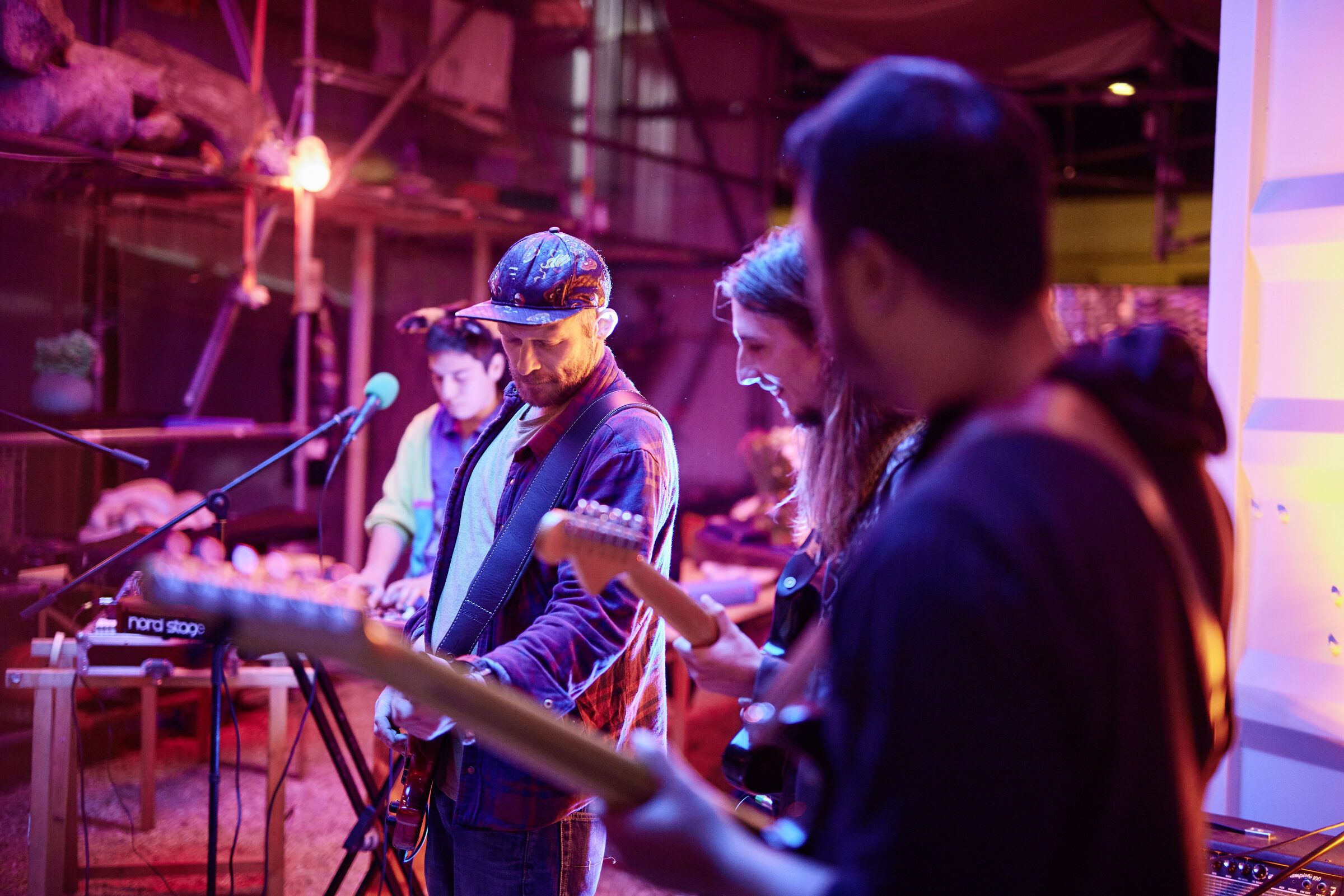 Musiker an Gitarren und Keyboard spielen im warmen Bühnenlicht.