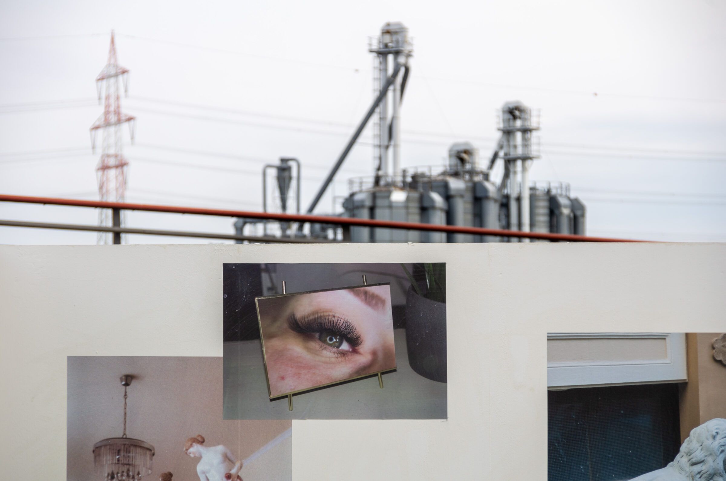Ein großformatiges Foto eines Auges an der Wand, darüber Silos und ein Strommast des Hafens.