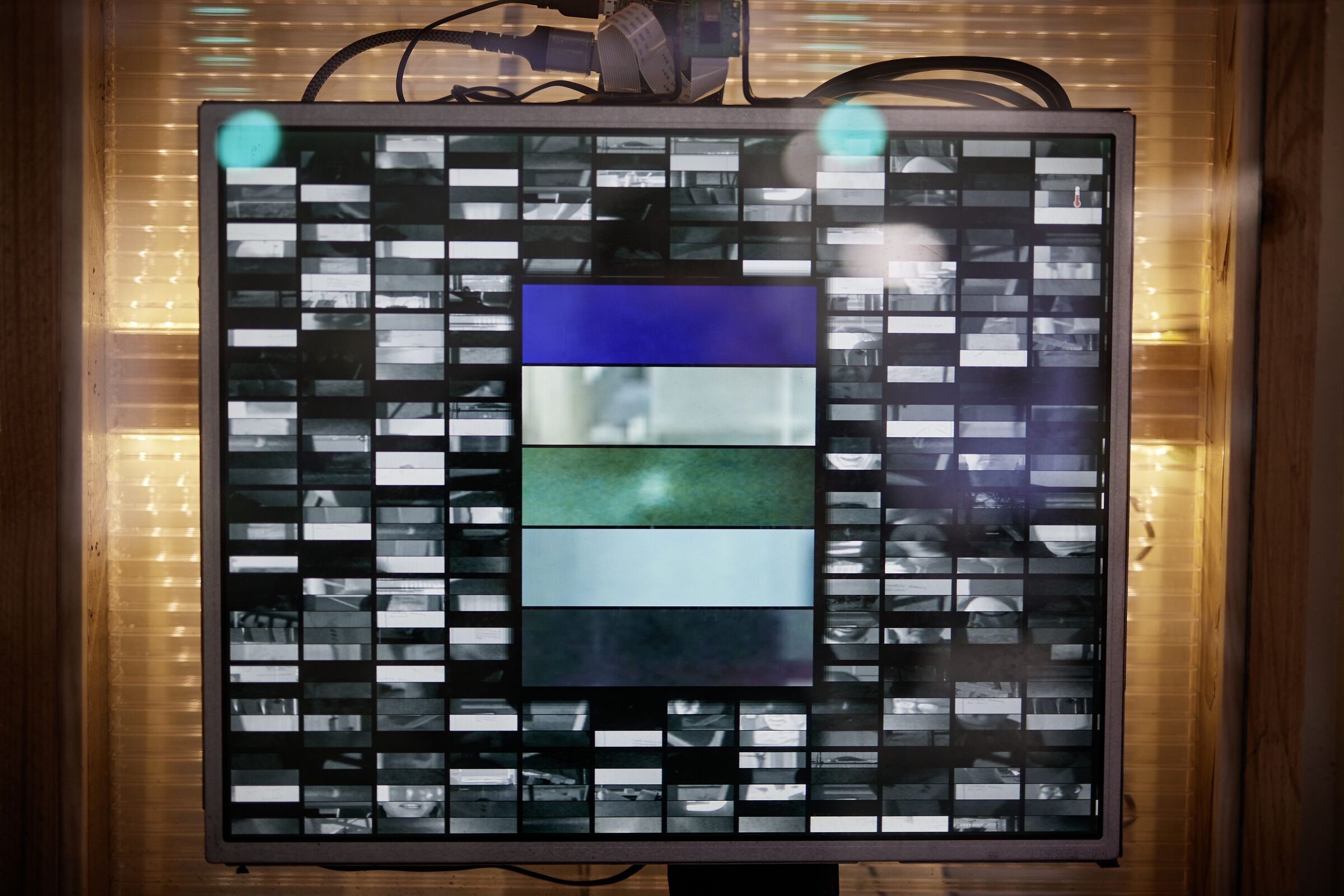 Ein Monitor zeigt ein Raster aus vielen kleinen Porträtausschnitten.