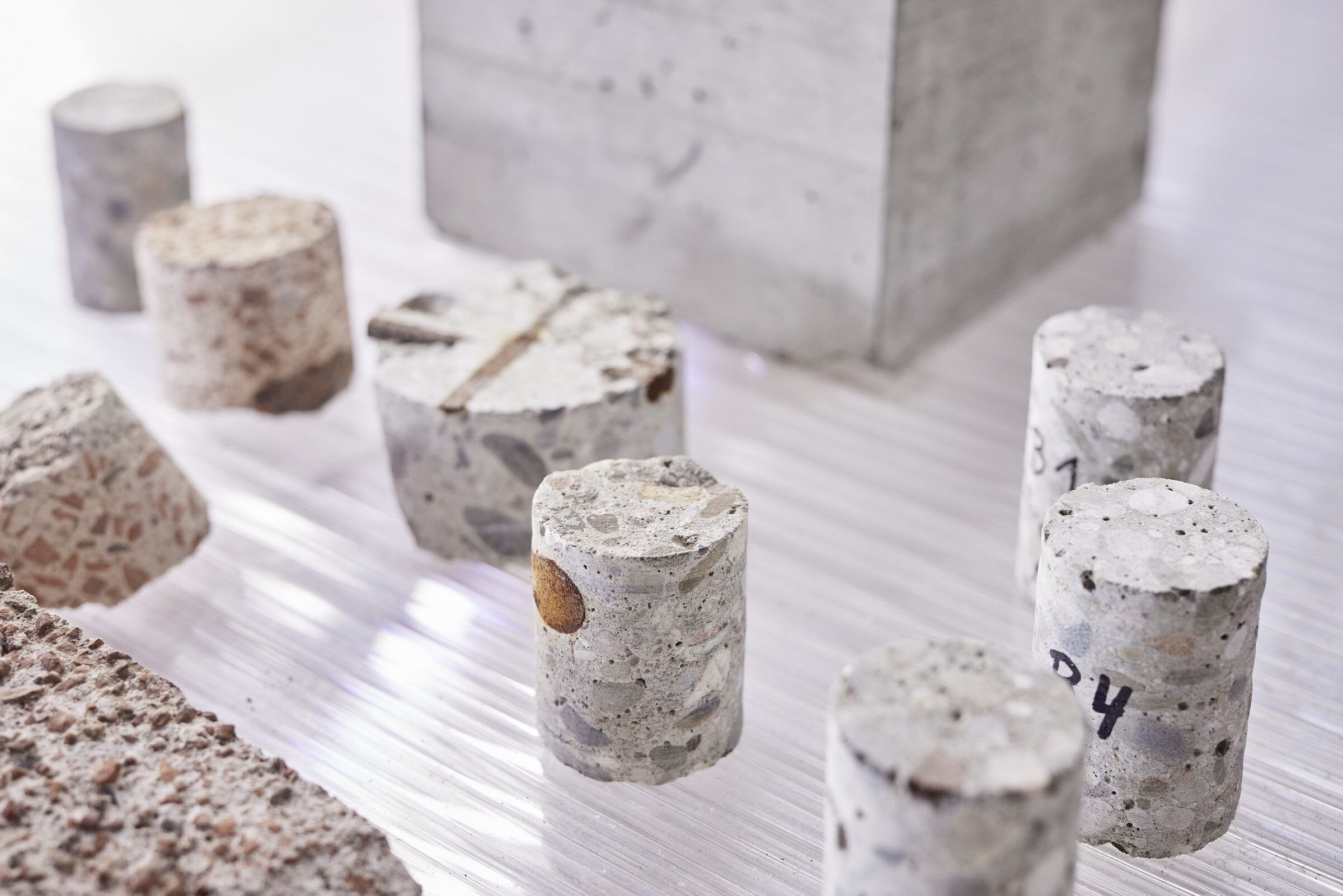 Bohrkerne aus Beton und Naturstein stehen vor einem Betonblock.