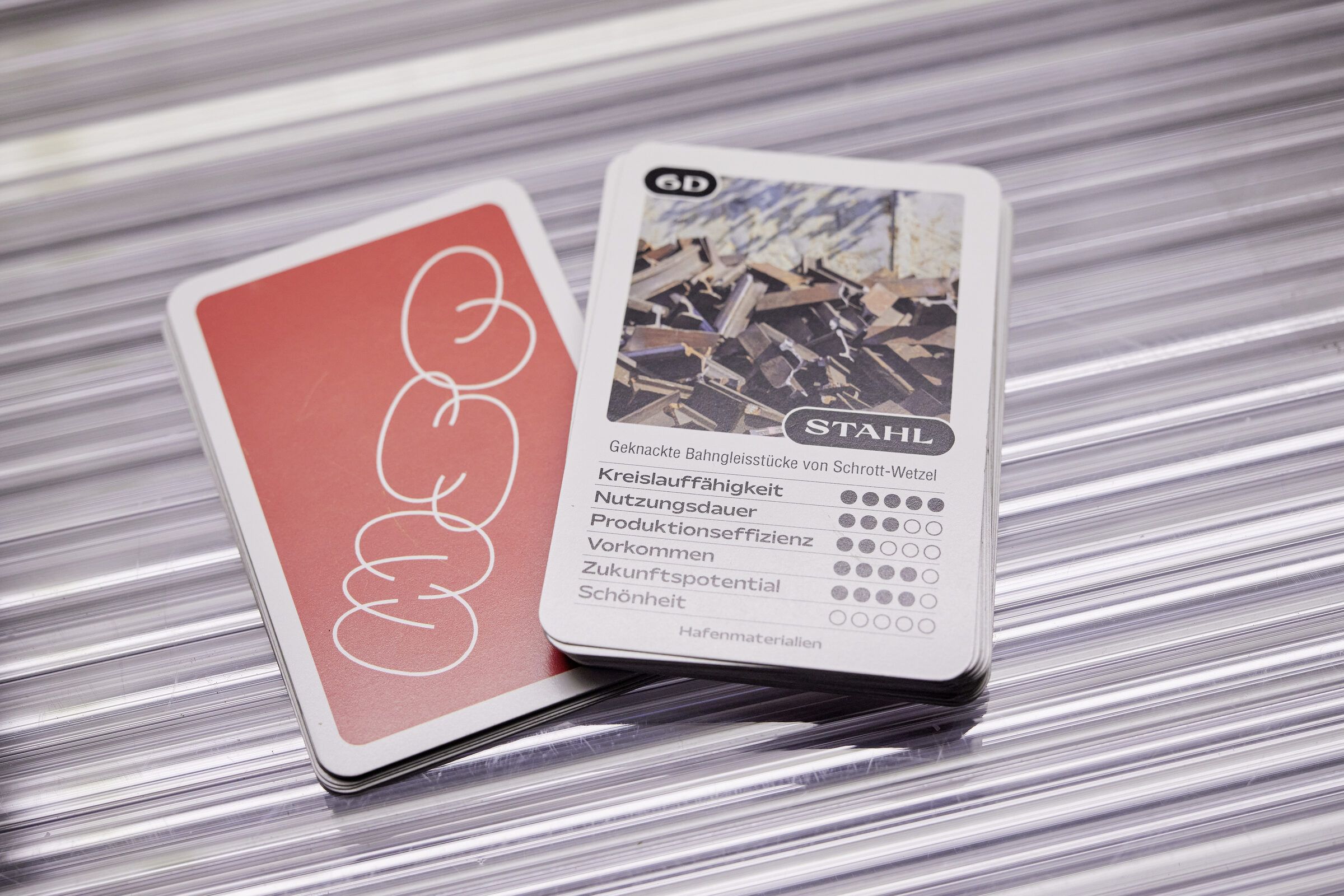 Zwei Karten des Material-Quartetts: eine rote Rückseite mit Logo und eine Vorderseite mit Foto und Werten.