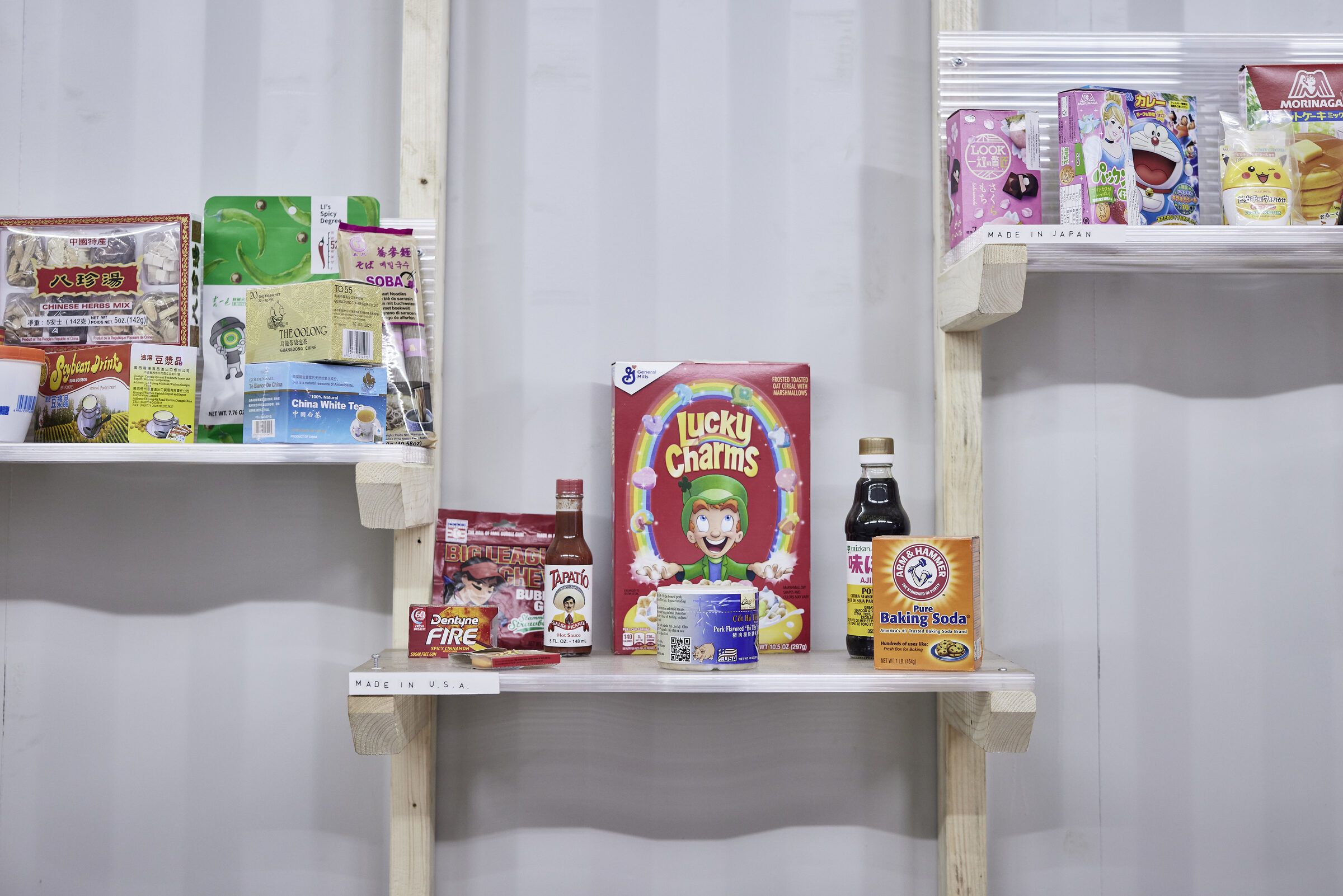 Wandregal mit Lebensmittelverpackungen und Konsumprodukten aus verschiedenen Ländern.
