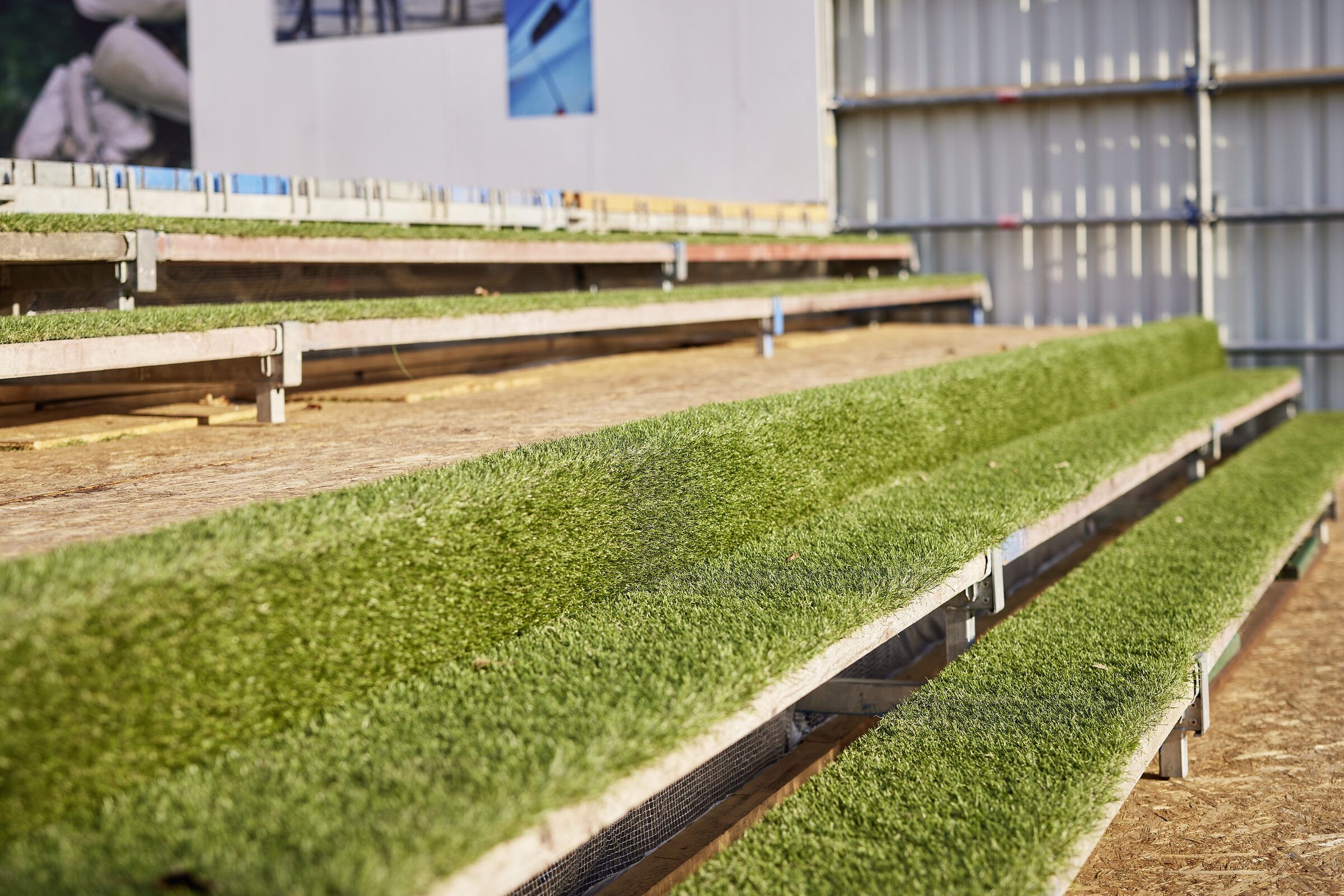 Stufen der Tribüne, zwischen den Holzbohlen wächst Gras in schmalen Streifen.